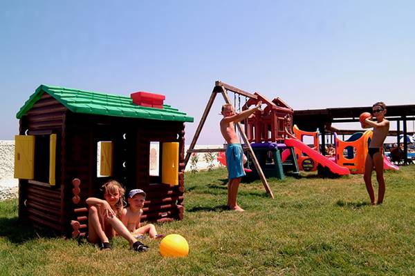 Kinder spielen auf einem Spielplatz im Freien am Hotel Themis Beach.