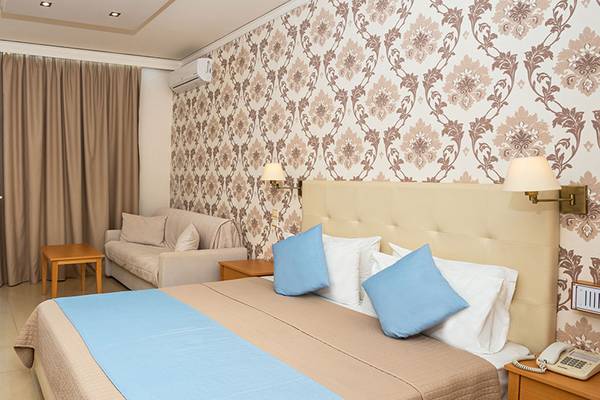 Hotelzimmer mit Meerblick und Balkon im Themis Beach Hotel, inklusive Schreibtisch, Stuhl, Sofa und Fernseher.