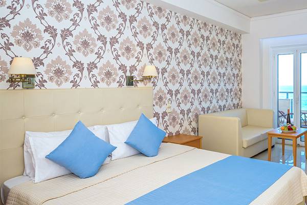 Das Zimmer im Themis Beach Hotel mit einem Bett, Kissen, Couch, Tisch und Blick auf das Meer.
