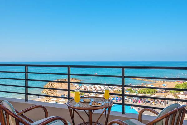 Terrasse mit Meerblick im Themis Beach Hotel mit zwei Gläsern Orangensaft und Plätzchen.