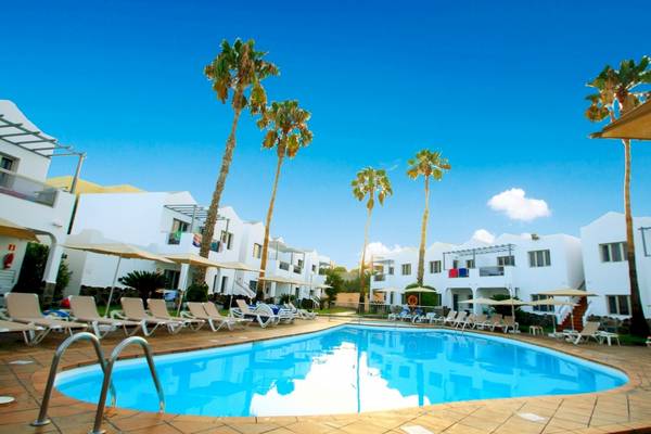 Poolbereich im Turbo Club mit weißen Gebäuden und Sonnenliegen unter Palmen.