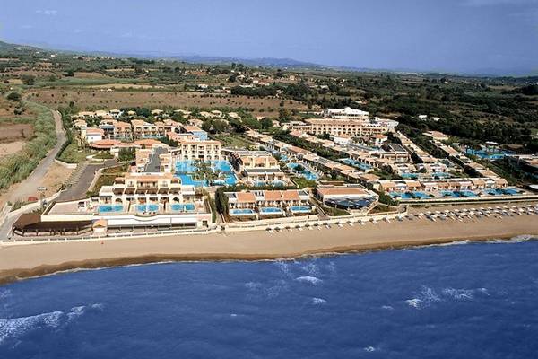 Luftaufnahme des Mitsis Royal Mare Thalasso & Spa Resorts mit mehreren Swimmingpools und einer langen Strandlinie.
