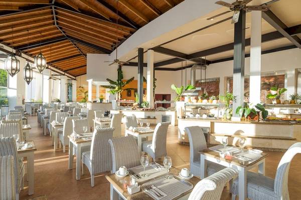 Innenansicht des Restaurants des BlueBay Villas Doradas Hotels mit Tischen, Stühlen und Pflanzen.