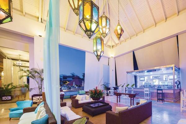 Innenbereich des BlueBay Villas Doradas Hotels mit farbigen Lampen, Sofas und einem Barbereich.