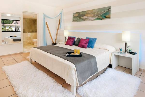 Schlafzimmer im BlueBay Villas Doradas Hotel mit Bett, Tisch, Lampen und Teppichen.