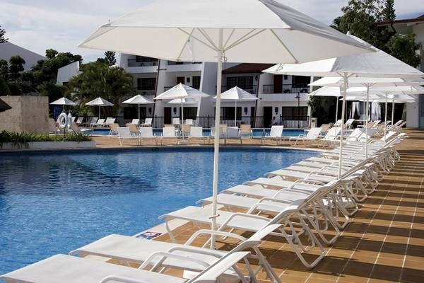 Poolbereich im BlueBay Villas Doradas Hotel mit vielen weißen Sonnenschirmen und Liegestühlen.