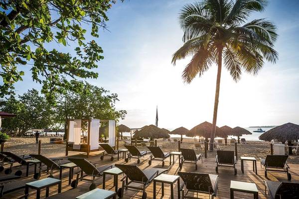 Strandlounge der BlueBay Villas Doradas mit Sonnenliegen und Palmen
