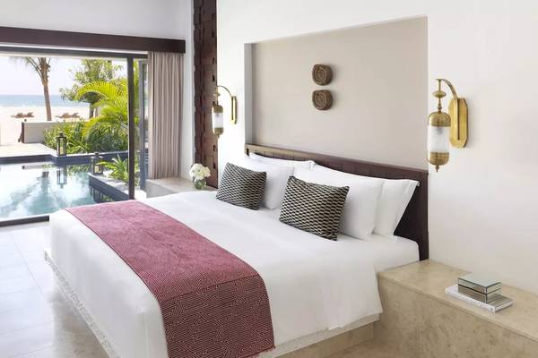 Ein modernes Hotelzimmer mit einem großen Bett und einem Pool, der zur Küste führt.