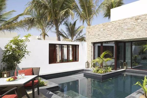Außenbereich des Al Baleed Resort Salalah by Anantara mit Swimmingpool und Garten