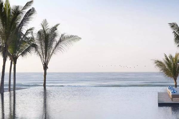 Pool mit Sonnenliegen und blauen Sonnenschirmen im Al Baleed Resort Salalah by Anantara