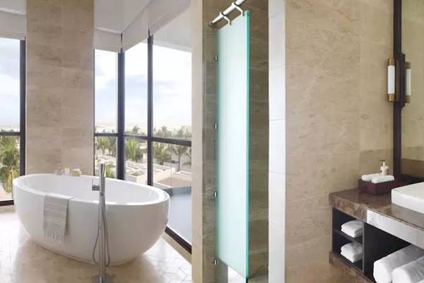Badezimmer im Al Baleed Resort Salalah von Anantara mit Badewanne und Fenstern.