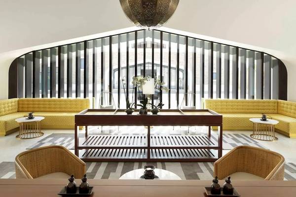 Innenansicht des Al Baleed Resorts Salalah by Anantara mit gelben Sofas, einem langen Tisch und großen Fenstern.
