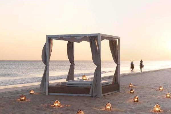 Al Baleed Resort Salalah by Anantara Bett am Strand mit Vorhängen und Lampen