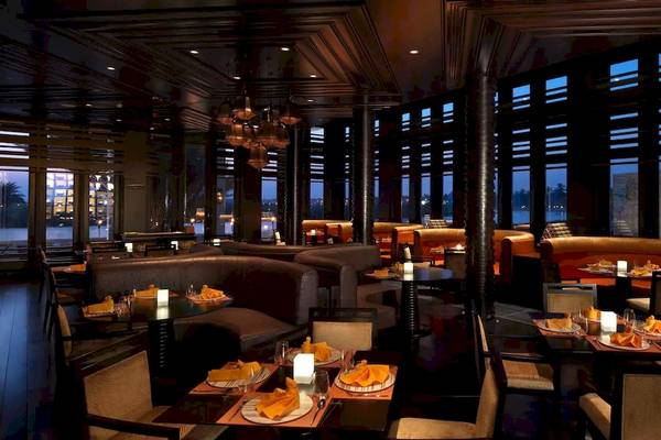 Innenansicht des Al Baleed Resort Salalah by Anantara Restaurants mit runden Tischen und Kerzen.