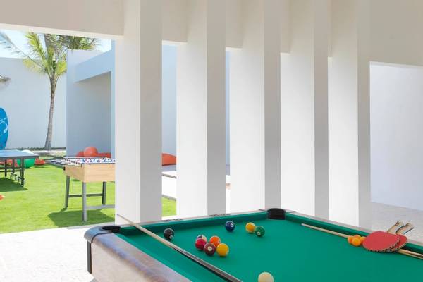 Außenspielbereich des Al Baleed Resort Salalah by Anantara mit Billardtisch, Tischtennisplatte und Palmen im Hintergrund.