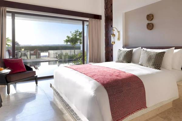 Hotelzimmer im Al Baleed Resort Salalah by Anantara mit Blick auf Terrasse und Garten.