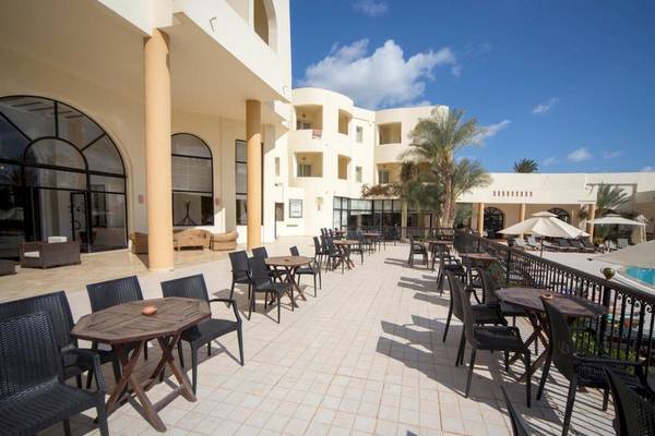 Außenbereich des Green Palm Hotels mit Tischen, Stühlen und Swimmingpool.