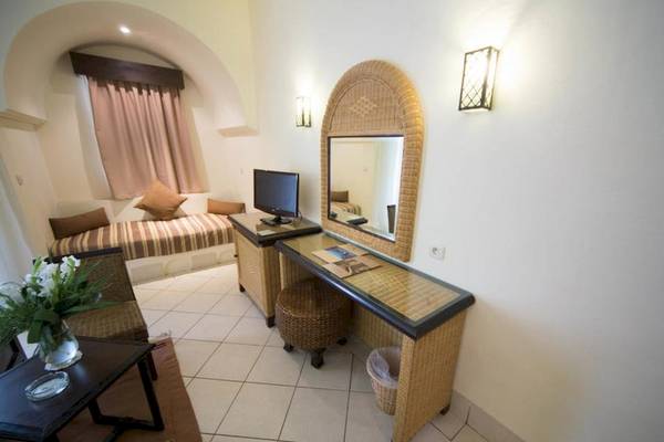 Innenansicht eines Zimmers im Green Palm Hotel mit Schreibtisch, Spiegel, Fernseher und Bett
