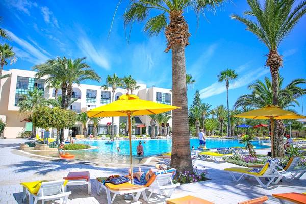 Außenbereich des Green Palm Hotels mit Pool, Liegestühlen und Sonnenschirmen.