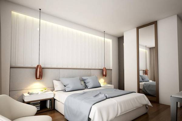 Innenansicht eines Schlafzimmers im NissiBlu Beach Resort mit weißem Bett, grauen Kissen und modernen Lampen.