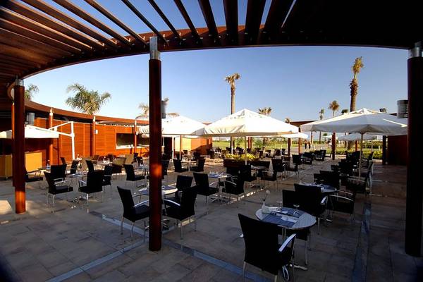 Terrasse des Calista Luxury Resort mit Tischen und Stühlen unter Sonnenschirmen