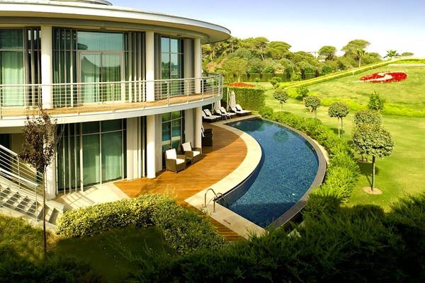 Außenansicht des Calista Luxury Resorts mit Swimmingpool und Garten.
