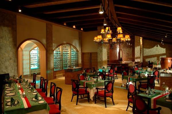 Restaurant im Calista Luxury Resort mit grünen Tischen und roten Stühlen.