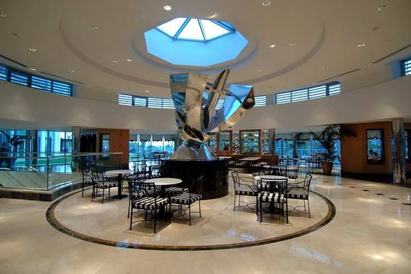 Foyer im Calista Luxury Resort mit zentraler Skulptur und umliegenden Tischen und Stühlen.