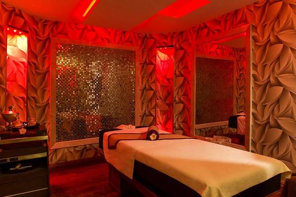 Massageraum im Calista Luxury Resort mit roten Beleuchtung und Blattmuster-Wandverkleidung.