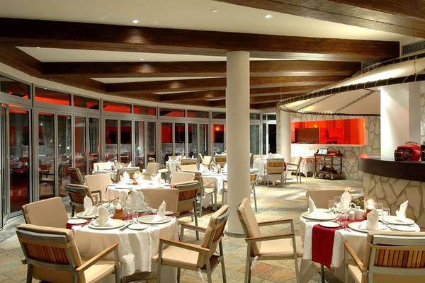 Innenansicht des Restaurants im Calista Luxury Resort mit gedeckten Tischen und Holzdecken.