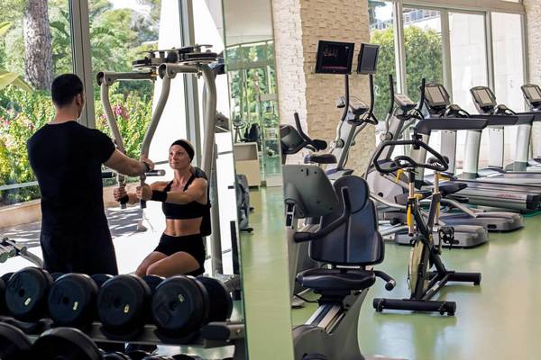 Fitnesstrainer hilft Frau im Calista Luxury Resort Fitnesscenter