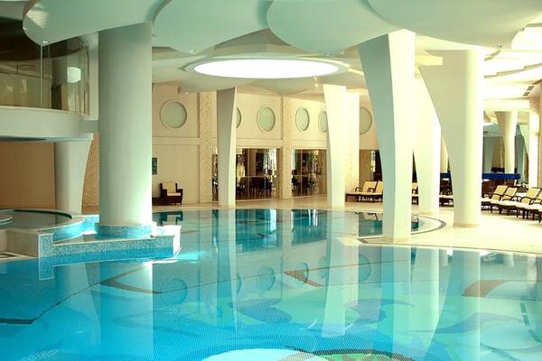 Innenpool im Calista Luxury Resort mit weißen Säulen und gefliestem Boden.