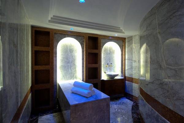 Spa-Bereich im Calista Luxury Resort mit Marmorwänden, Beleuchtung und einer Liege mit Handtüchern.