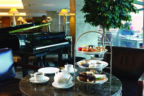 Im Swissotel Buyuk Efes Izmir Lounge mit einem Klavier, einer Teekanne, einer Tasse und einem Etagentablett mit Snacks.