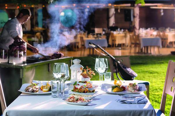 Grillfest im Garten des Swissotel Buyuk Efes Izmir mit einem Koch, der Essen zubereitet und rauchendes Holzkohlegrill.