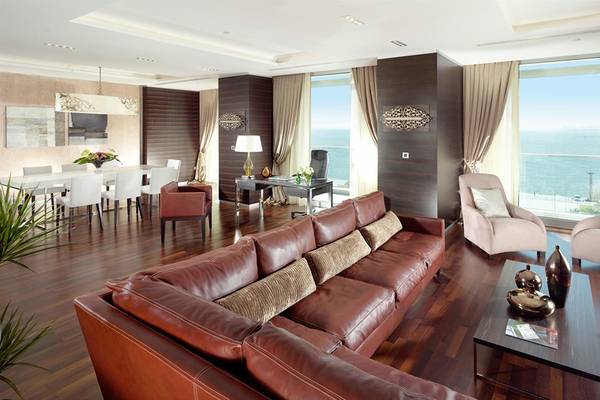 Wohnzimmer im Swissotel Buyuk Efes Izmir mit Meerblick, braunes Ledersofa und eleganter Einrichtung.