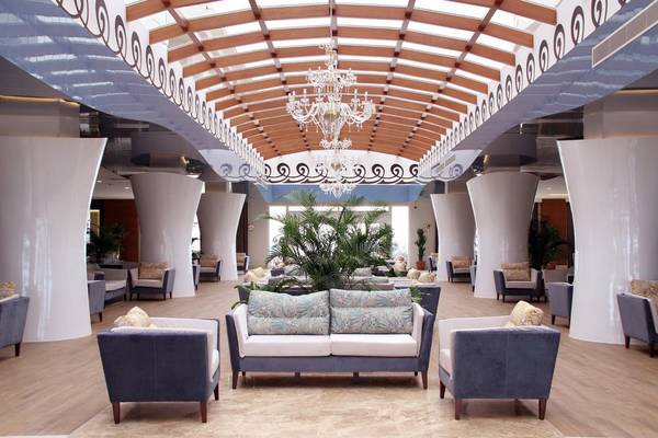 Innenansicht der Lobby des Adalya Ocean Deluxe Hotels mit weißen Säulen und einem Kristall-Chandelier.
