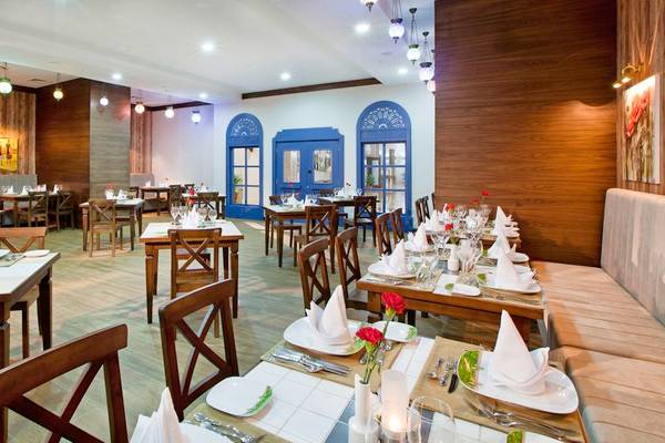 Innenansicht des Restaurants des Adalya Ocean Deluxe Hotels mit gedeckten Tischen und dekorierten Wänden.