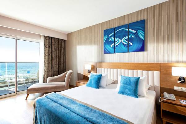 Hotelzimmer im Adalya Ocean Deluxe mit Blick auf das Meer von einer großen Glastür aus.
