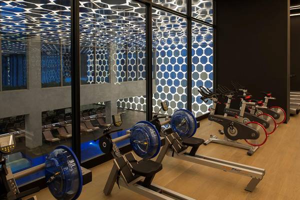 Fitness-Center im Maxx Royal Kemer Resort mit gemusterter Decke und Reihe von Crosstrainern.
