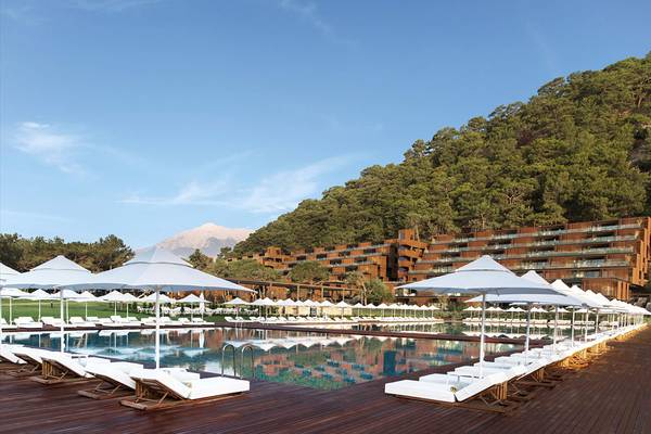 Poolbereich des Maxx Royal Kemer Resort mit vielen weißen Sonnenliegen und Sonnenschirmen.