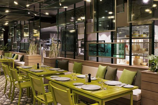 Innenbereich des Restaurants im Maxx Royal Kemer Resort mit grünen Tischen und Stühlen.