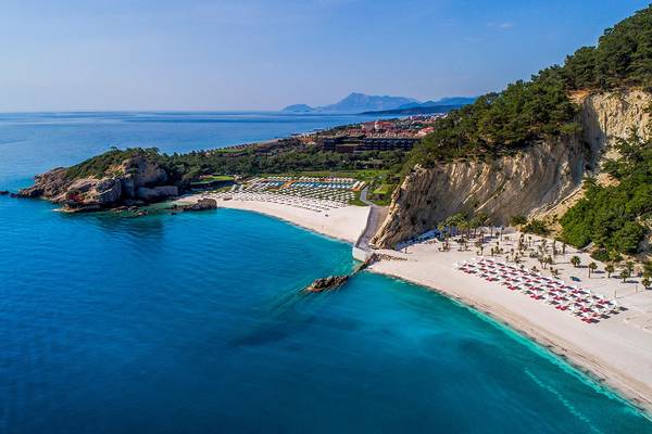 Luftaufnahme des Maxx Royal Kemer Resorts mit blauem Meer, weißen Stränden und vielen Sonnenliegen.