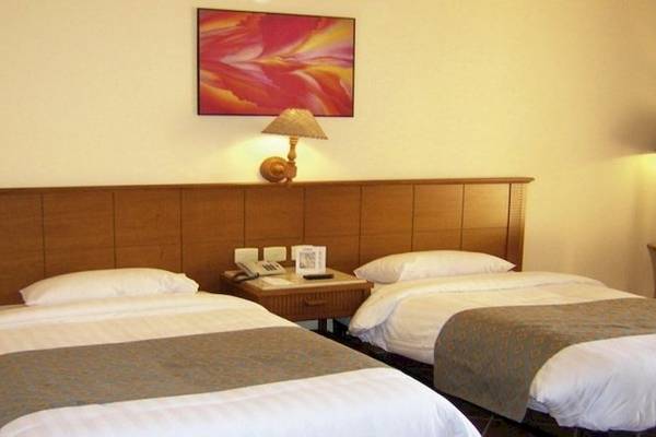Doppelbettzimmer im Charmillion Garden Aqua Park Hotel mit zwei Betten, Nachttischen und Lampen.