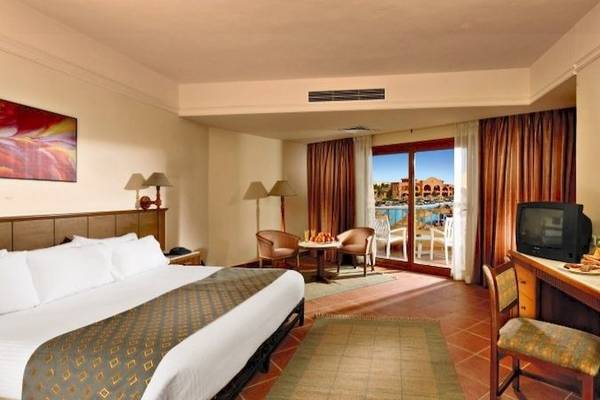 Zimmer im Charmillion Garden Aqua Park Hotel mit großem Bett, Schreibtisch und Balkon.