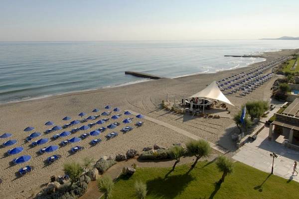 Luftaufnahme des Aquila Rithymna Beach Hotels mit Strand und vielen blauen Sonnenschirmen.