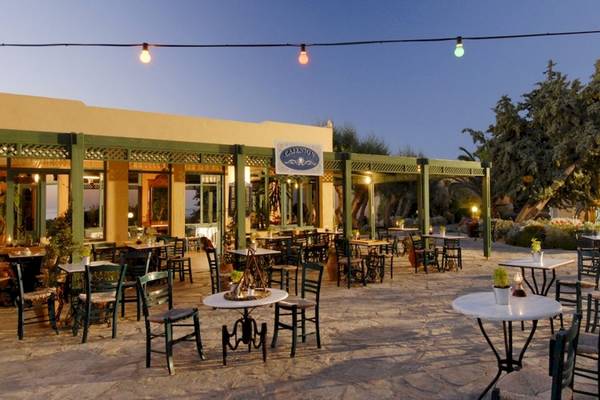 Außenbereich des Aquila Rithymna Beach Hotels mit Tischen und Stühlen, beleuchteten Laternen und Pflanzen.