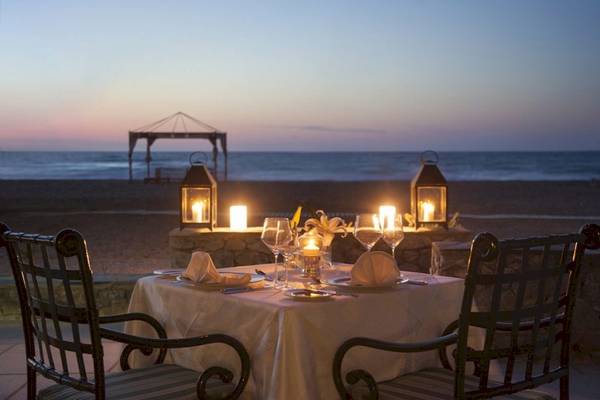 Ein romantisches Abendessen am Strand des Aquila Rithymna Beach Hotels mit Kerzen und Blick auf das Meer.