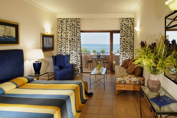 Aquila Rithymna Beach Hotel Zimmer mit Balkon und Meerblick, mit Bett, Sofa, Tisch, Stühlen und Dekoration.
