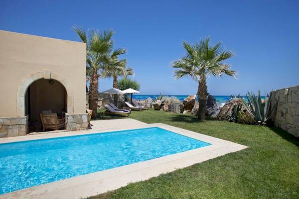 Außenpool des Aquila Rithymna Beach Hotels mit Liegestühlen und Palmen